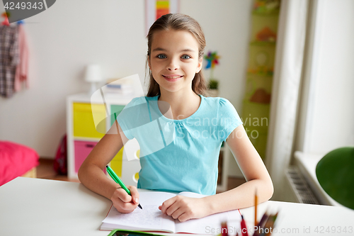 Image of happy girl writing to notebook at home