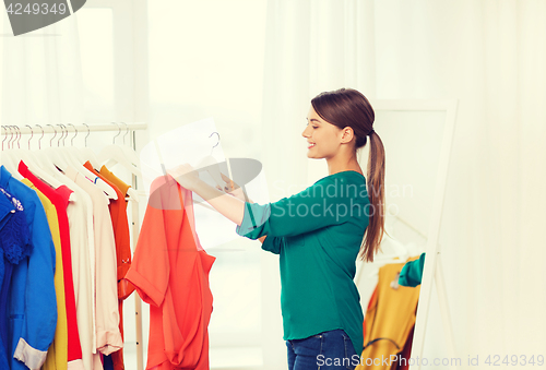 Image of happy woman choosing clothes at home wardrobe