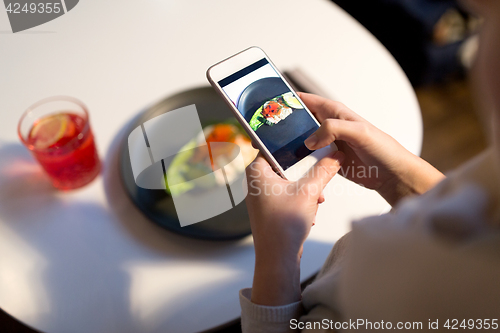 Image of woman with smartphone photographing food at cafe