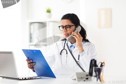 Image of doctor with clipboard calling on phone at hospital