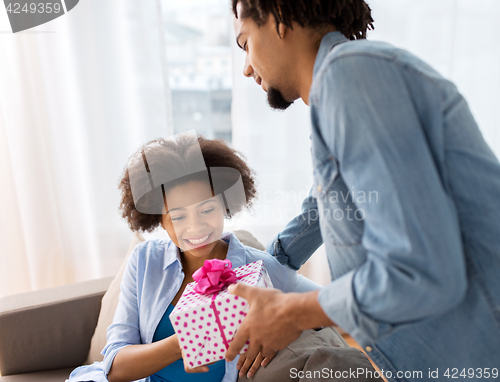 Image of happy couple with gift box at home