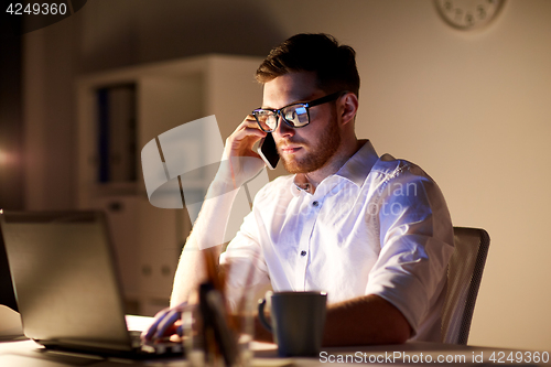 Image of businessman calling on smartphone at night office