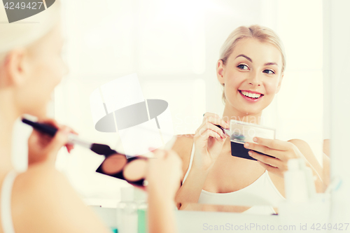 Image of woman with makeup brush and foundation at bathroom