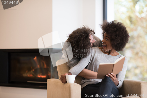 Image of multiethnic couple hugging in front of fireplace