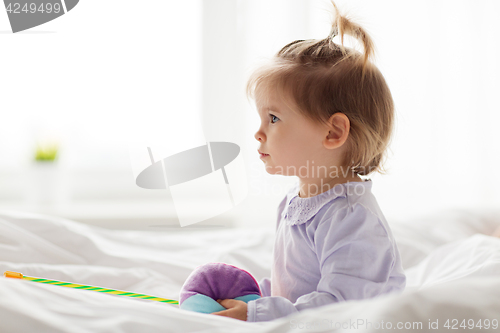 Image of lovely little girl with toys in bed at home