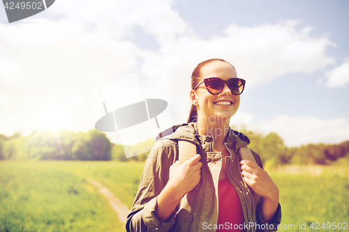 Image of happy young woman with backpack hiking outdoors