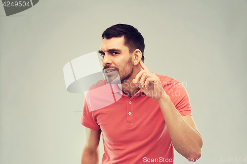 Image of man having hearing problem listening to something