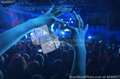 Image of The silhouettes of concert crowd in front of bright stage lights