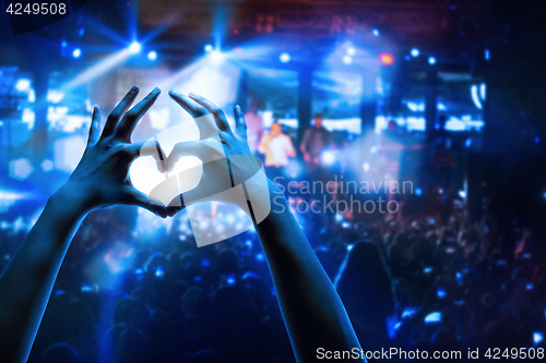 Image of The silhouettes of concert crowd in front of bright stage lights