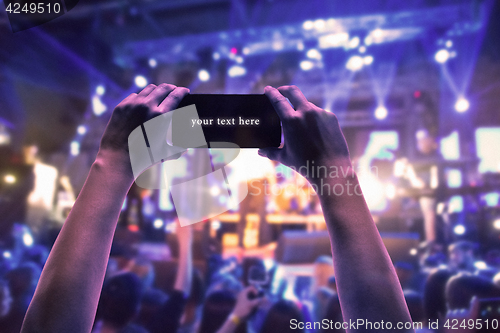 Image of The silhouettes of concert crowd in front of bright stage lights