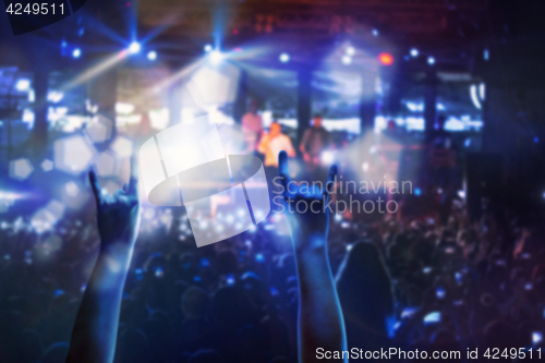 Image of The silhouettes of concert crowd in front of bright stage lights