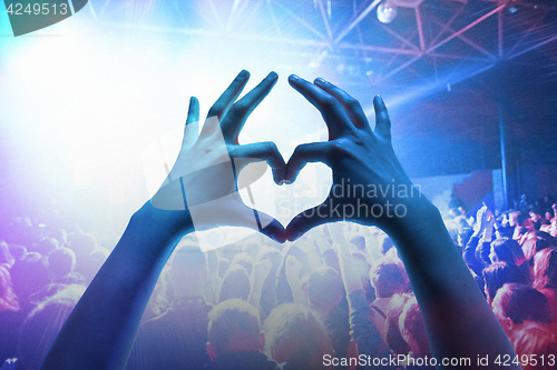 Image of The silhouettes of concert crowd in front of bright stage lights