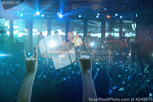 Image of The silhouettes of concert crowd in front of bright stage lights