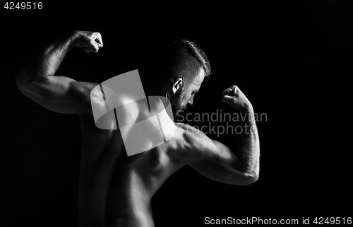 Image of The back view torso of attractive male body builder on black background.