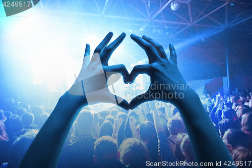 Image of The silhouettes of concert crowd in front of bright stage lights