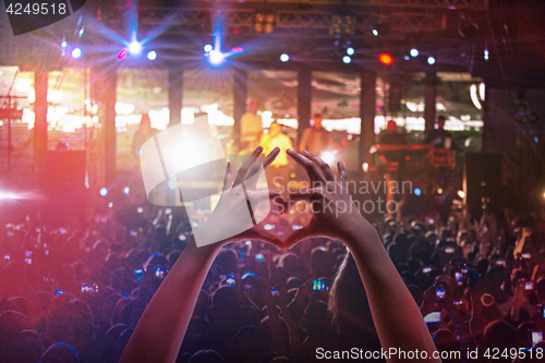 Image of The silhouettes of concert crowd in front of bright stage lights