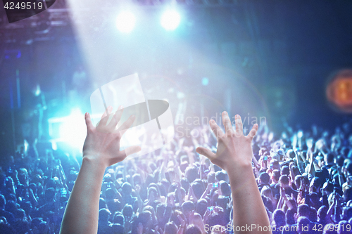 Image of The silhouettes of concert crowd in front of bright stage lights