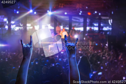 Image of The silhouettes of concert crowd in front of bright stage lights