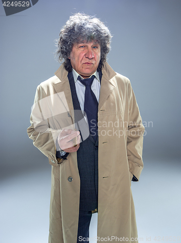 Image of The senior man with cigar as detective or boss of mafia on gray studio background