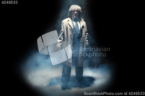 Image of Senior police agent with a gun on dark smoke background