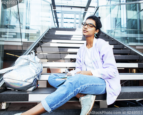 Image of young cute indian girl at university building sitting on stairs 