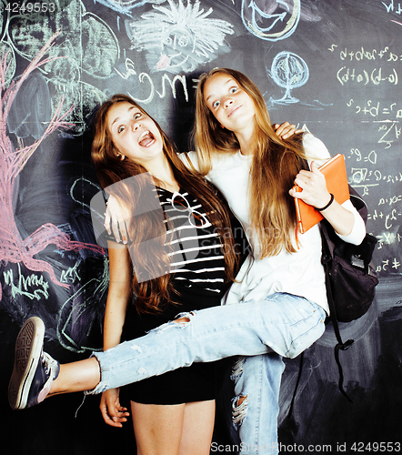 Image of back to school after summer vacations, two teen real girls in classroom with blackboard painted together, lifestyle people concept