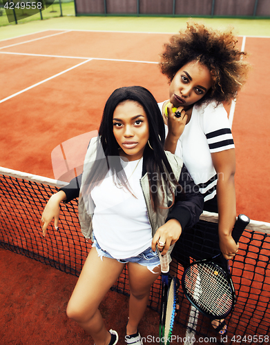 Image of young pretty girlfriends hanging on tennis court, fashion stylis