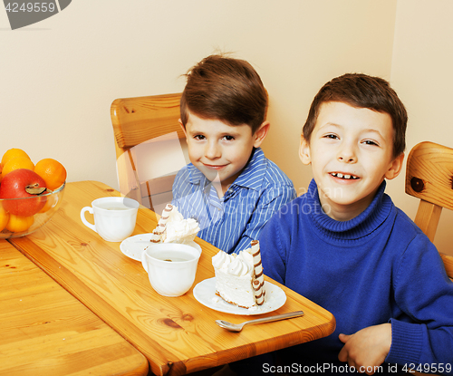 Image of little cute boys eating dessert on wooden kitchen. home interior