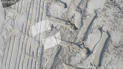 Image of Sandy background with prints of wheels and footprints