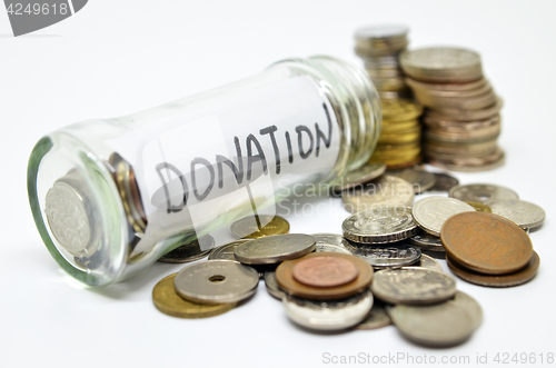Image of Donation lable in a glass jar with coins spilling out