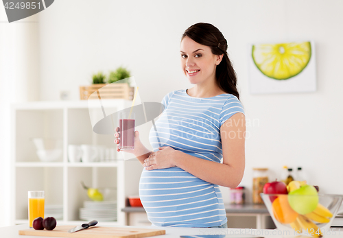 Image of happy pregnant woman drinking juice at home