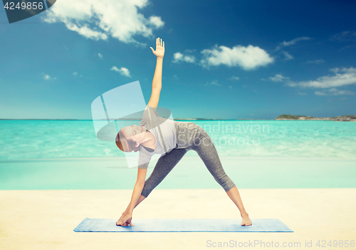 Image of woman making yoga triangle pose on mat