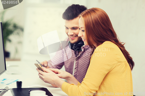 Image of smiling creative team with smartphones at office