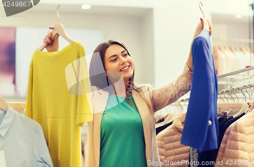 Image of happy young woman choosing clothes in mall