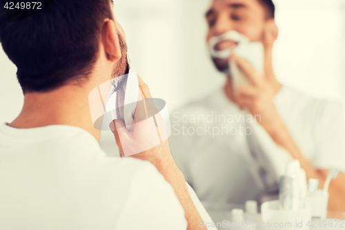 Image of close up of man removing shaving foam from face