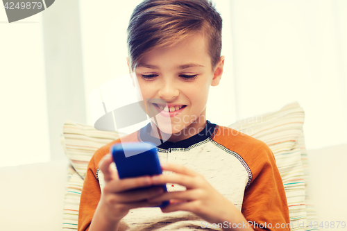 Image of boy with smartphone texting or playing at home