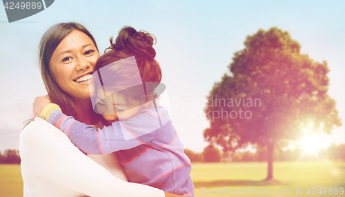 Image of happy mother and daughter hugging outdoors