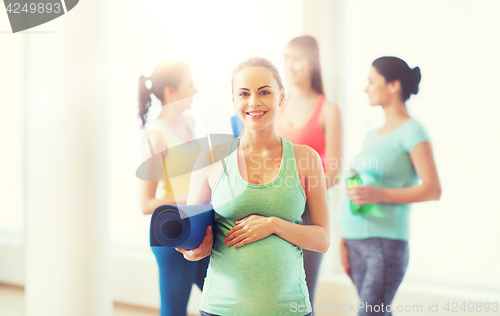 Image of happy pregnant woman with mat in gym