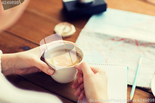 Image of close up of hands with coffee cup and travel stuff