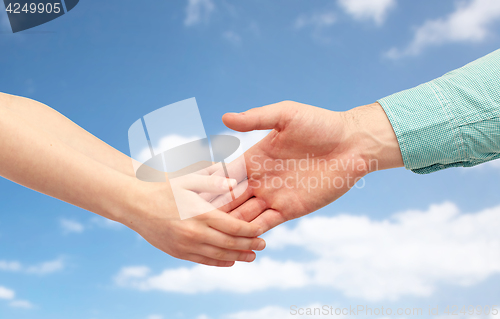 Image of father and child holding hands over blue sky