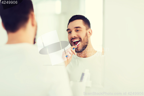 Image of man with toothbrush cleaning teeth at bathroom