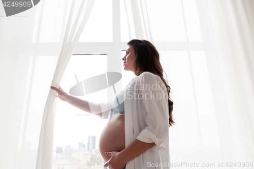 Image of happy pregnant woman with big tummy at home