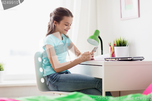 Image of girl with laptop and smartphone texting at home