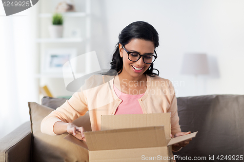 Image of happy young indian woman with parcel box at home