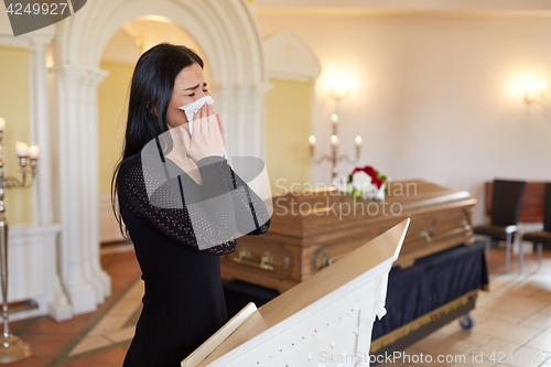Image of woman crying near coffin at funeral in church