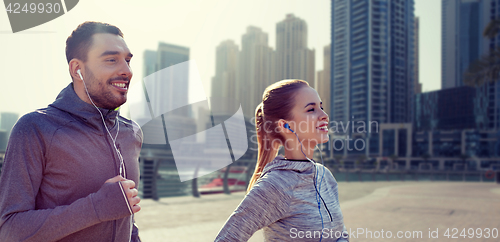 Image of happy couple with earphones running in city