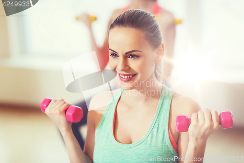 Image of smiling woman with dumbbells exercising in gym