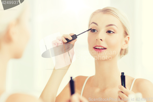 Image of woman with mascara applying make up at bathroom