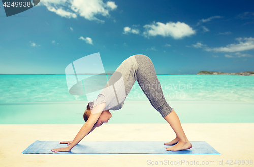Image of woman making yoga dog pose on mat