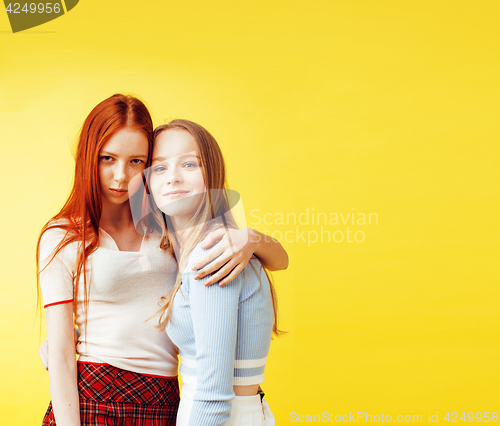 Image of lifestyle people concept: two pretty young school teenage girls having fun happy smiling on yellow background 